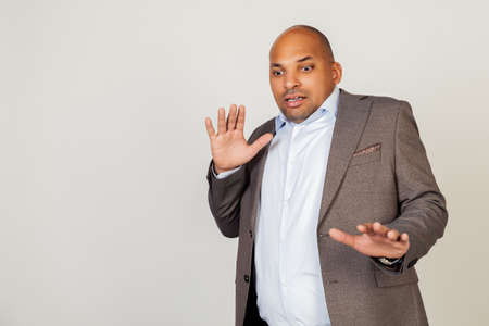 Portrait of shocked young African American businessman guy, scared and frightened by fear expression, stopped hand gesture, shouting in shock. Panic concept. Standing on a gray background.の写真素材