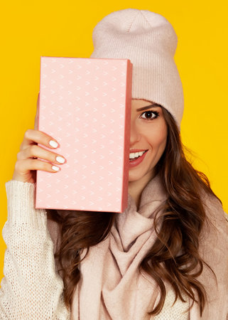 Happy young woman with a gift box in her hands, covers half of hの写真素材