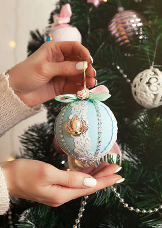 Close-up of female hands hang the ball on the tree. Christmas deの写真素材