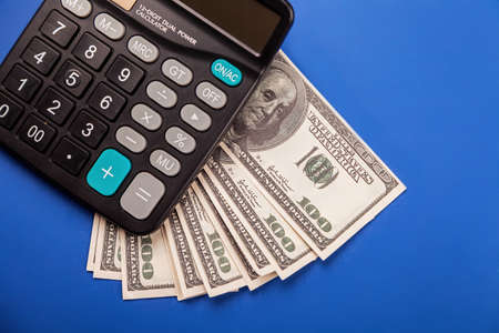 Money and calculator calculation. USD banknotes and a calculator. Planning budget, using calculator checking finances, counting bills or taxes, online banking servicesの写真素材