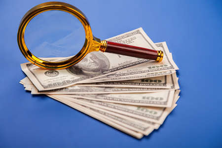 Money with a magnifying glass. Finding profits and losses. A business concept with a magnifying...