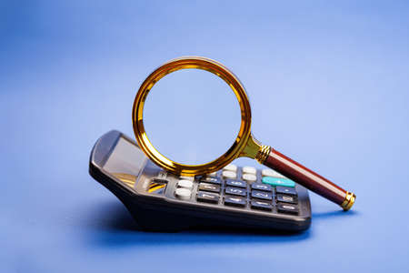 Business concept with magnifying glass and calculator. Math, cost, tax or investmentの写真素材