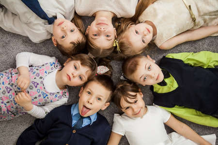 Boys and girls in circle. Happy children having fun. kids lay down together. Happy children lying on...