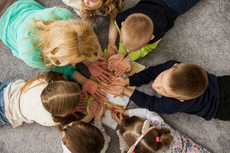 Boys and girls in circle. Happy children having fun. kids lay down together. Happy children lying on the floor in a circle with hands. Top view. Group of children beautiful smile lying on the floorの写真素材