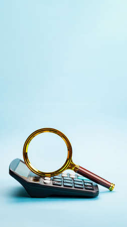 Business concept with magnifying glass and calculator. Math, cost, tax or investmentの写真素材