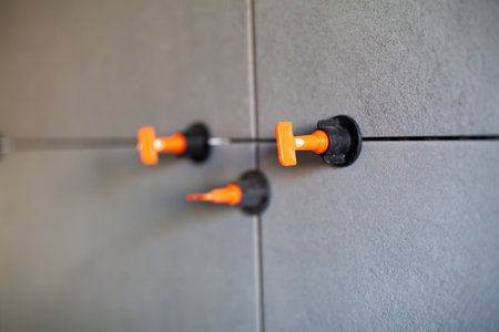 Tile leveling system with plastic clips.Tile leveling system. Tiler installing large format tile on wall. tile leveling systemの写真素材