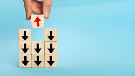 Businessman hand picked wooden block with red arrow facing the oの写真素材