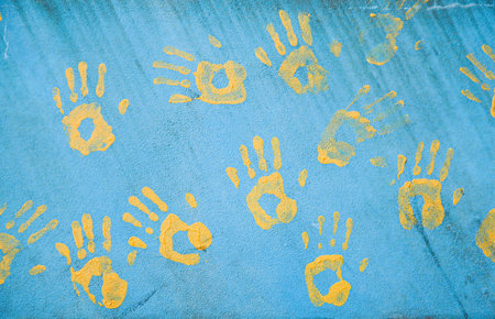 Handprints on the wall. Yellow prints on a blue wall. The background of the concept of friendship....