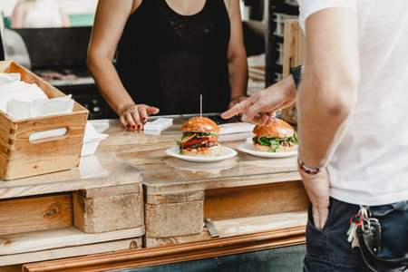 Man chooses burgers at a burger feast. Dinner Hamburger Food Feast Party. Big burger in hands at street food outdoor festivalの写真素材
