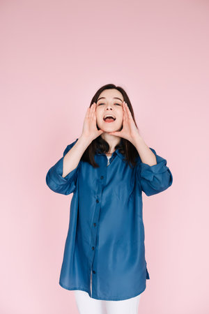 Expressive Joy: Close-Up Portrait of a Cheerful Young Womans Hands near Open Mouth, Conveying Excitement and Happiness with a Toothy Smile, Isolated on Vibrant Pink Backgroundの写真素材