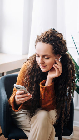 Relaxed woman browsing modern apps and texting messages on smartphone at home. Happy lady using mobile phone for internet browsing and online shopping. Mobile phone user messaging, shopping from homeの写真素材