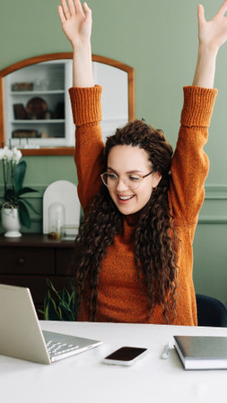 Excited Young Woman Celebrating Online Success on Laptop - Job Approval or Exam Results Achieved Winning Online and Receiving Email Approval for Exam Results or Job Opportunity.の写真素材