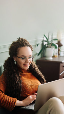 Young woman enjoying online shopping and elearning on laptop at home. Home shopping and elearning with a happy woman using laptop on sofa.の写真素材