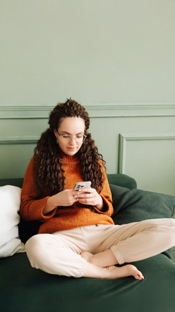 Happy Woman Relaxing on Sofa Using Cell Phone for Shopping and Social Media at Home - Ecommerce and Social Media Conceptの写真素材