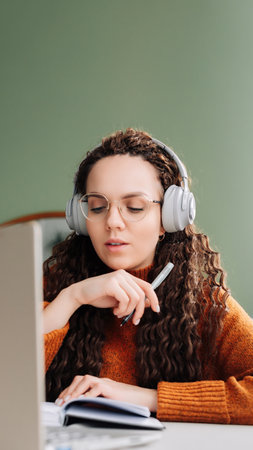 Female Student in Home Office Learning and Working on Laptop. Young Woman Engaged in Remote Learning and Work at Home. Online Study and Work Concept with Young Woman on Laptopの写真素材
