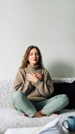 Beautiful young woman in lotus pose on bed practicing pranayama breathing techniques, finding inner balance after a stressful dayの写真素材