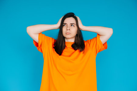 Unsatisfied Girl Touching Head, Frustration Concept - Empty Space, Disgruntled Expression, Isolated Blue Backgroundの写真素材