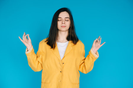 Serene Young Woman Practicing Yoga Meditation - Relaxation, Balance, Mindfulness, Serene Relaxation, Inner Peace, Mindfulness, Isolated on Blue Backgroundの写真素材