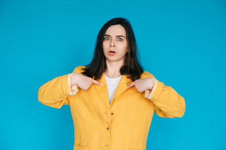 Young Frustrated University Student Pointing Fingers at Herself, Feeling Unhappy and Angry - Exam Stress, Forgetfulness, Isolated on Blue Backgroundの写真素材