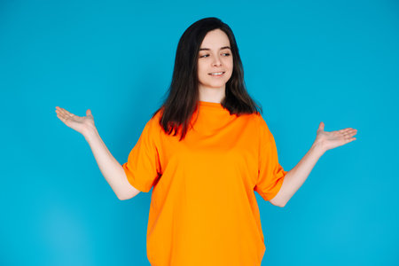 Smiling Young Woman Holding Empty Copy Space in Palms, Attractive Female Model, Isolated on Bright Blue Background, Portrait Photoの写真素材
