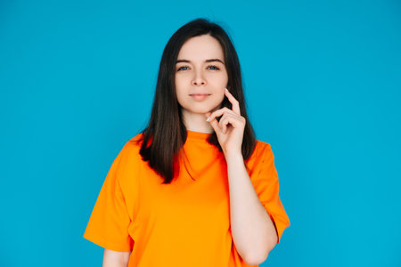 Thoughtful Woman Touching Chin, Contemplating, Copy Space, Isolated on Blue Background. Portrait of a Beautiful Woman Touching Her Chin, Contemplatingの写真素材
