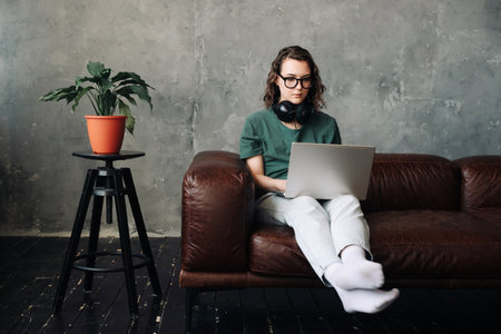 Digital Freelance Lifestyle: Young Woman Working or Studying from Home on Laptop - Emphasizing Remote Learning, Business, and Modern Living Conceptsの写真素材