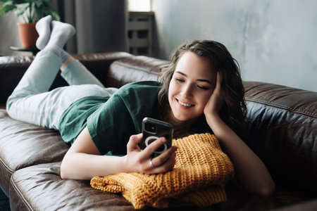 Technology and Youth: Home-Based Student Engaging in Mobile Texting and Study - Online Communication, Remote Learning, and Modern Lifestyle Conceptの写真素材