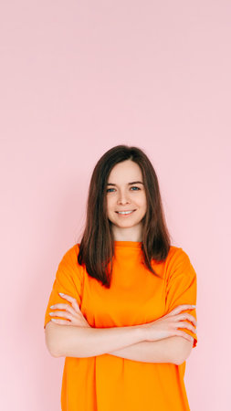 Radiant Joy: Beautiful Woman with Beaming Smile and Arms Crossed, Embracing Good Mood in Comfortable Attire - Vibrant Positivity on Pink Backgroundの写真素材