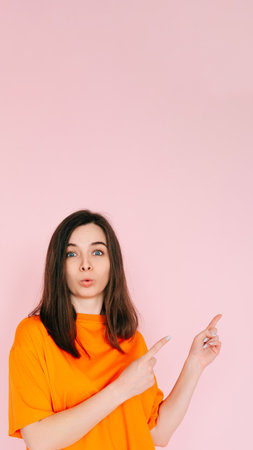 Engaging Playfulness: Humorous Woman Pointing Two Fingers at Empty Space - Interactive Concept with a Touch of Humor, Vibrant Pink Backgroundの写真素材