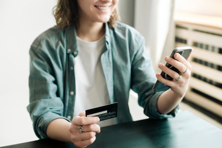 Woman holding credit card and using smartphone at home, businesswoman shopping online, e-commerce,...
