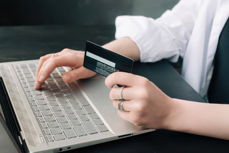 Elegance in E-commerce. Woman's Hands Grasp Credit Card, Navigate Online Shopping with Laptop - Conceptual Image. Chic Shopper. Woman Using Laptop and Credit Card for Online Purchase.の写真素材