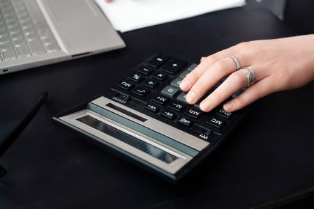 Efficient Financial Management. Woman Accountant Uses Calculator and Laptop, Both in Office and...