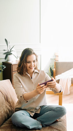 Woman Embracing Digital Connection. Reading Messages, Socializing on Social Media, and Playing Mobile Games on Smartphone Happy Young Female Engaging in Modern Digital Communication and Entertainment.の写真素材