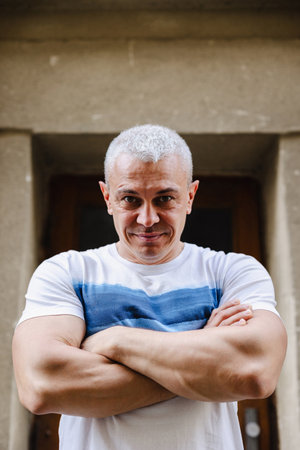 A man is standing with his arms crossed. He is smiling and he is confidentの写真素材