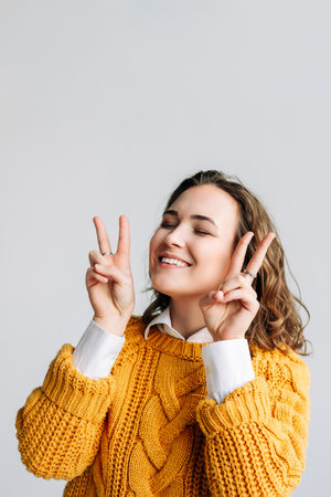 Young Woman Model Poses with Joyful Gestures - Cheerful, Playful, and Pretty - Smiling and Laughing with Victory and Peace Signs - Positive and Cute Expression - Joyful Isolation on White Backgroundの写真素材