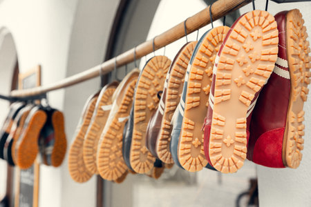 A collection of vintage sneakers with distinctive rubber soles hanging on a wooden rod in a European...