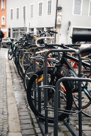 Row of urban bicycles parked in a metal bike rack along a cobblestone street. The European cityscape...
