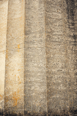 Old stone column showing vertical grooves and a rough, weathered texture. The aged surface and...