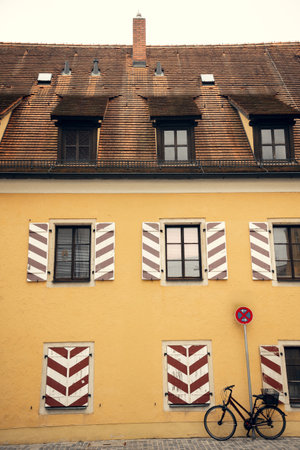 A beautiful European house with classic wooden shutters and a bicycle leaning against its yellow facade. The historic architecture and warm tones create a cozy, nostalgic atmosphereの写真素材