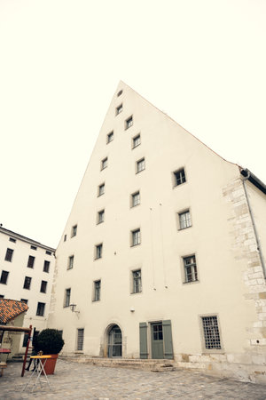A striking triangular historic building with medieval architecture and multiple windows, located in Regensburg, Germany. Ideal for travel, history, and architectural projectsの写真素材