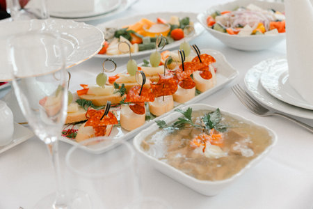 Festive table with assorted appetizers including canapes, cold dishes and salads, symbolizing...
