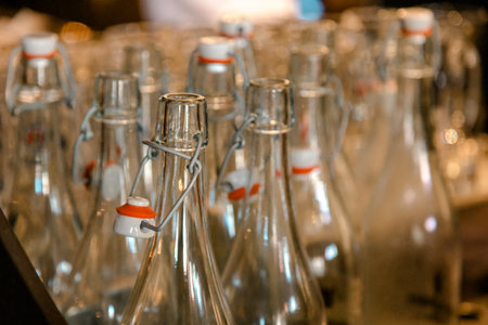Many transparent glass bottles with classic swing-top caps, perfect for home brewing, kitchen decor, or sustainable product packaging. Captured with a warm, cozy light.の写真素材