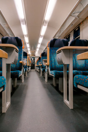 Empty modern train cabin with blue patterned seats and bright lighting, showing contemporary design and comfort in public transportation. Ideal for travel, editorial, or lifestyle visuals.の写真素材