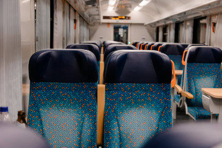 Unoccupied seats in a contemporary train carriage, with distinctive blue and orange patterns. Evokes themes of travel, efficient public transport, and a peaceful journey ahead.の写真素材