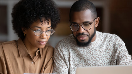 Close-up of a focused African American man and woman in glasses working together. The mood is collaborative and professional. Ideal for business, teamwork, or educational concepts.の素材