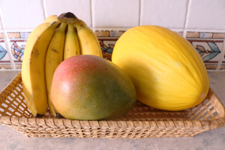 Fruit basket with bananas, mango and melonの写真素材