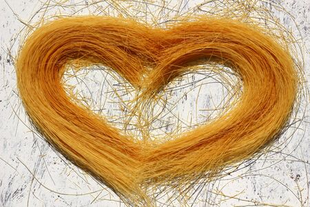 Uncooked Vermicelli Pasta in the Shape of a Heart on a Wooden Backgroundの写真素材