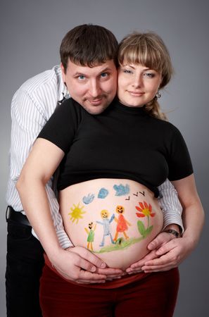 Man tenderly embracing his wife with a painted belly.の写真素材