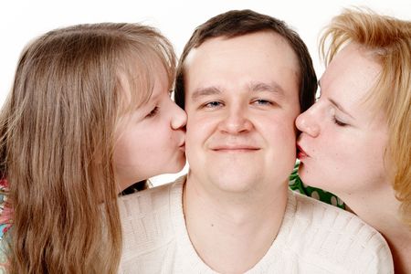 His wife and daughter kissing a happy man. Close-up.の写真素材