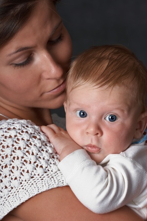 Young woman holds  baby. Dark background, studio shotの写真素材
